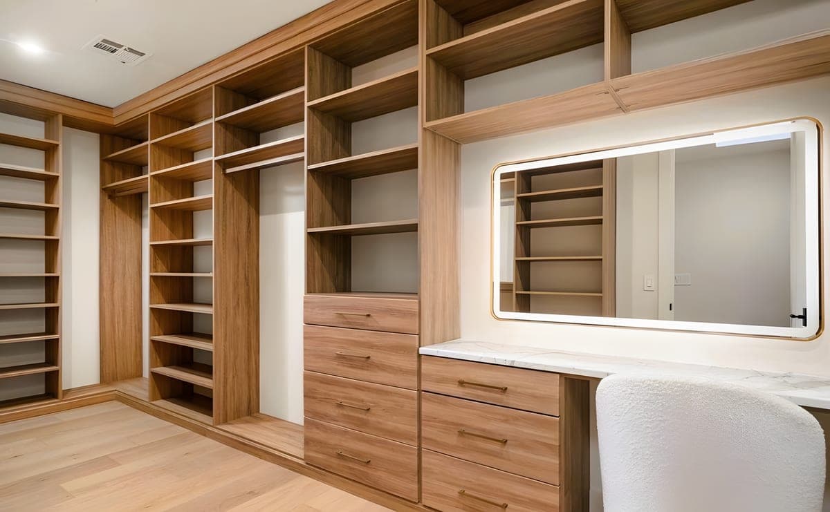 Walk-in dressing room with custom walnut built-in closet system, integrated marble-top vanity, shoe shelving, and brass hardware