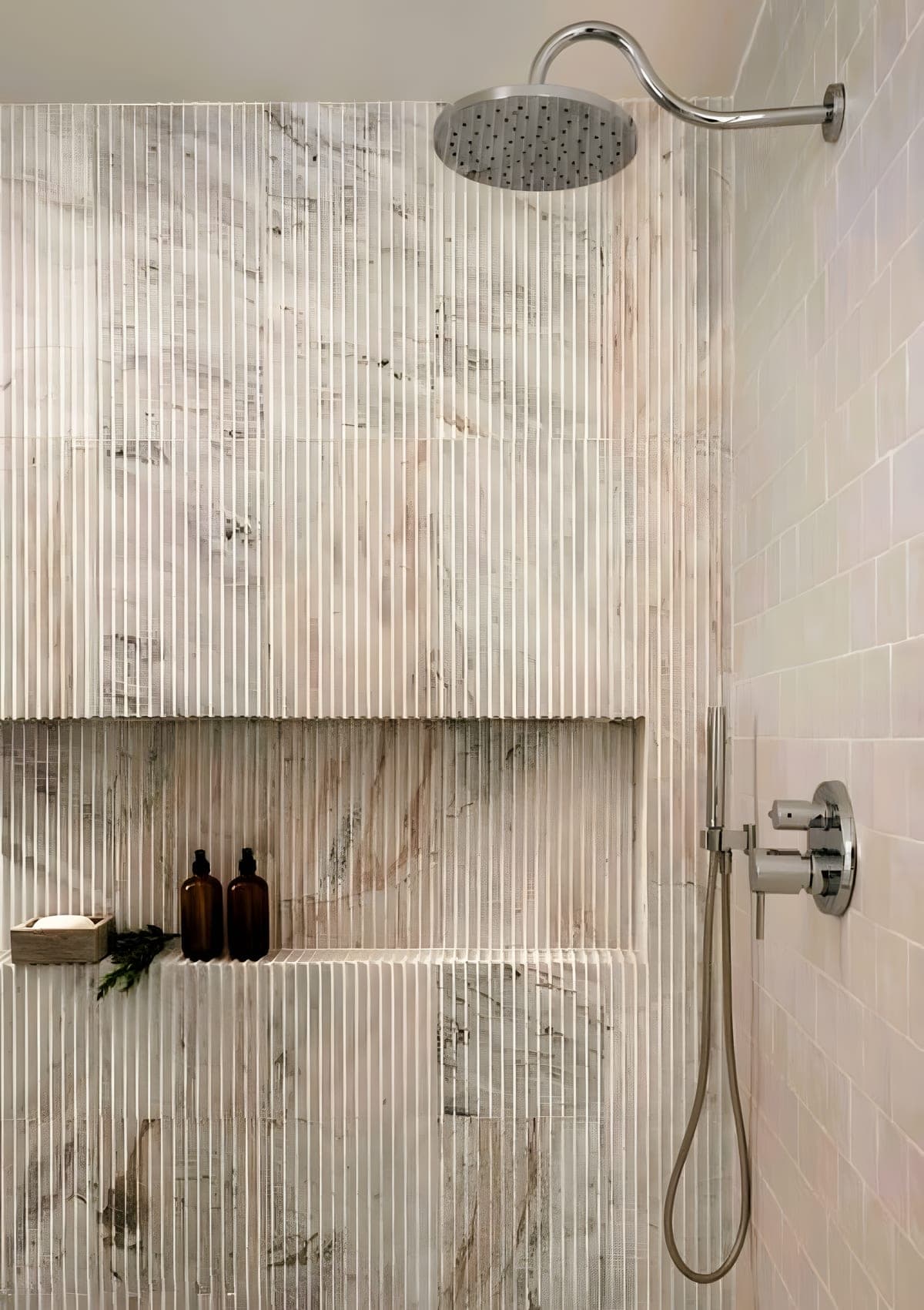 Close-up of fluted marble tile in a walk-in shower with a recessed niche and rain shower head